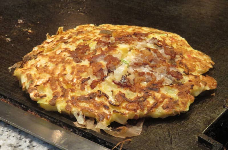 cooking okonomiyaki on the griddle