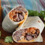 A carnitas burrito cut in half
