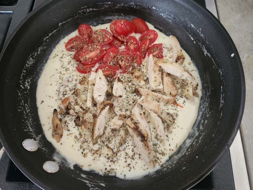 Adding chicken and tomatoes to the saucepan.
