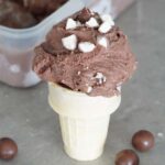 A scoop of chocolate malted crunch ice cream in a cone