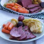Corned beef slices on a plate with carrots, potatoes and cabbage