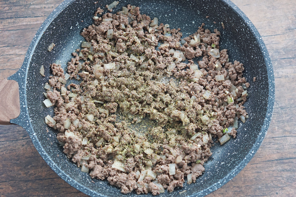 cooking the ground beef and onions then adding spices.