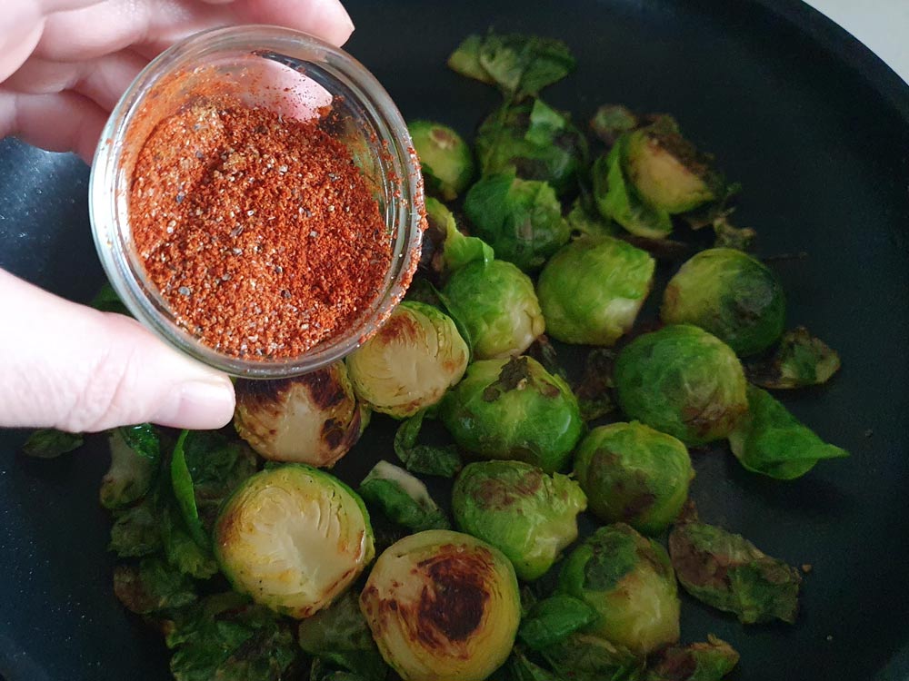 pouring spice mix on brussels sprouts