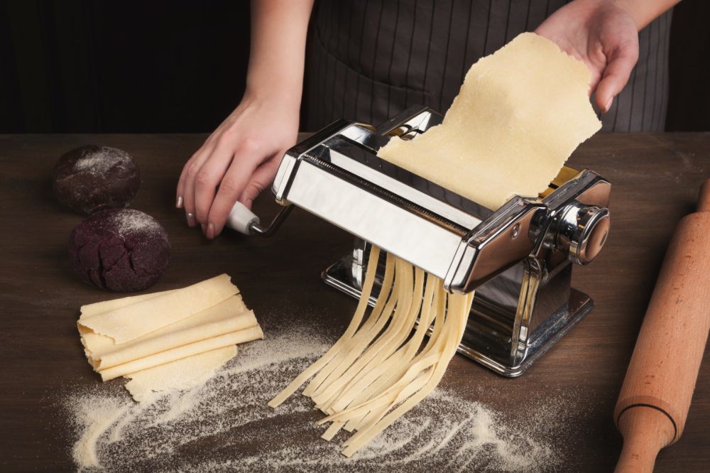 Rolling a sheet of pasta through a pasta maker